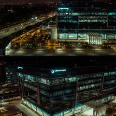 A dramatic night-time aerial shot of the Collins Aerospace building in Bengaluru. Our low-light drone photography highlights the building's modern design and illumination against the city skyline.
