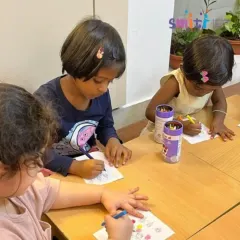 A group of children sits together at a table, each working on their own Eid-themed artwork. This fosters a sense of community while allowing for individual expression.