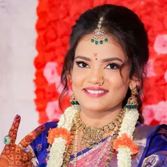 A close-up bridal portrait that captures her bright smile and the fine details of her makeup and jewelry against a vibrant floral background.
