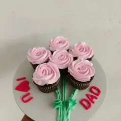 A creative cupcake bouquet for Father's Day. I arrange six pink rosette cupcakes on a board and add frosting stems to look like a bunch of flowers, with an "I ❤️ U DAD" message.