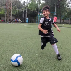 This is the pure joy of football we aim to inspire in every child. A young player breaks away with the ball, a huge smile on his face, embodying the fun and freedom at the heart of our coaching philosophy.