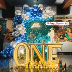 A stunning setup for a first birthday, featuring a shimmering blue sequin wall that creates a fantastic photo backdrop. We paired it with a blue and silver balloon arch, a large light-up "ONE" table, and personalized marquee letters for a truly memorable party look.