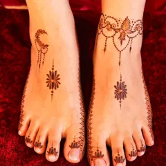 A minimalist and modern foot mehandi design, featuring a crescent moon on one foot and a delicate floral pattern on the other.
