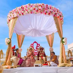 A beautiful daytime wedding ceremony under a stunning floral mandap. We capture the grandeur of your wedding setup and the sacred rituals, ensuring every detail of the ceremony is preserved against a bright, clear sky.
