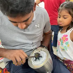 Curiosity knows no age. We love seeing moments like this, where a young girl watches with fascination as a mentor works on a kitchen appliance. Our workshops are safe, welcoming spaces for kids to learn practical skills.