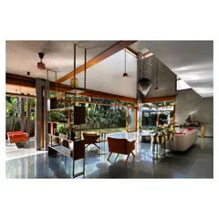 Inside the House of Canopies, a triple-height living area dissolves into the garden through floor-to-ceiling glass. The polished concrete floor reflects the changing daylight from the skylight above, creating a dynamic interplay of light and shadow that makes the space feel alive.