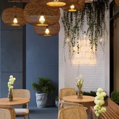 A closer look at the details that create the ambiance. The cascading vines on the white brick wall, paired with the warm glow of the neon sign and woven light fixtures, create a perfect corner that is both rustic and modern.