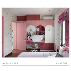 This view showcases the integrated study unit in a dreamy pink kid's room. The desk is built into the wardrobe, with open shelving for books and toys, creating a functional space for both play and learning. The heart-patterned wallpaper adds a whimsical touch.