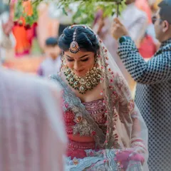 The bride's gentle smile as she walks under the phoolon ki chadar. This is a classic Indian bridal entry shot, filled with tradition and emotion.