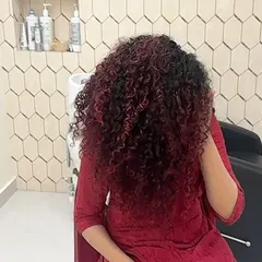 A full view of this stunning red balayage on long, beautiful curls. The color is strategically placed to create dimension and movement, making the curls pop. This shows how vibrant color can work in harmony with natural texture.