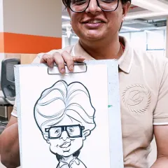 A happy employee from a corporate event holding his personalized caricature. It's a great way to make team members feel appreciated.