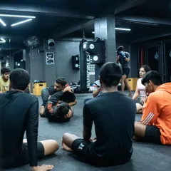 I demonstrate a grappling technique to a circle of students. This focused instruction ensures everyone understands the details of the move before they practice it.