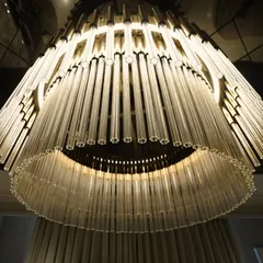 A close-up of a tiered glass rod chandelier. This fixture is not just a source of light but a sculptural centerpiece that adds glamour and sophistication.