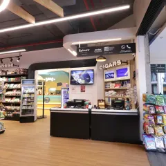 The checkout counter at Epicure is designed for efficiency and to showcase last-minute purchase items like cigars and snacks. The overhead lighting and clear branding ensure a smooth and pleasant end to the shopping experience.