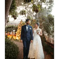 The bride and groom take a quiet walk together moments after their first look. The beautiful garden path and hanging lights of the Gallops Mumbai venue create a fairytale setting for this romantic pre-vow portrait.