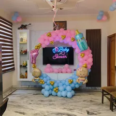 I create fun and stylish decorations for baby showers. This setup features a circular frame with a 'Baby Shower' neon sign, surrounded by pink and blue balloons, and accented with cute baby-themed foil balloons.