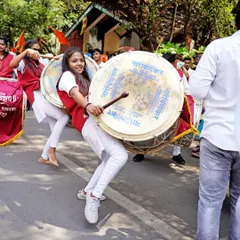 The power and rhythm of the dhol-tasha pathak. I use a dynamic angle to photograph the performers, conveying the sheer energy of their movements during the street festival.