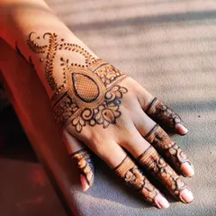 A perfect example of a simple yet elegant party henna. This design features a prominent central element on the back of the hand, with delicate patterns on the fingers, leaving some skin showing for a modern look.