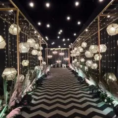 For a truly dramatic and modern entrance, I can design something unique like this. The combination of a black and white chevron carpet, geometric lanterns, and warm fairy lights creates an unforgettable walkway for your guests.