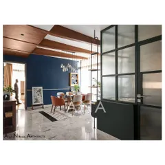 The dining space in Apartment 704 is defined by a bold blue feature wall and antique wooden ceiling beams. This creates a vibrant, playful atmosphere for hosting, in contrast to the more minimal living area.
