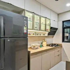 This compact kitchen design maximizes storage with floor-to-ceiling cabinets. The fluted glass upper cabinets with internal lighting add a touch of elegance, while the neutral color scheme makes the space feel open.