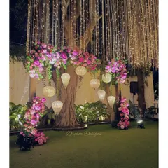 Pink hues and elegant chandeliers set the mood for this reception. I used clusters of pink flowers and hanging lanterns to decorate the space around a large tree, creating a natural yet glamorous focal point.
