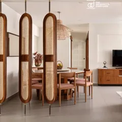 A view into the dining area of the 'Rooted Japandi Home'. The design uses natural materials like wood and rattan, seen here in the custom partition and dining set, to create a space that is both elegant and warm, influenced by Japanese and Scandinavian principles.