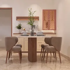 This dining space is designed for cozy meals. The four-seater table with a fluted wood base is complemented by a custom-built crockery and pooja unit in the background, featuring lattice-work doors.