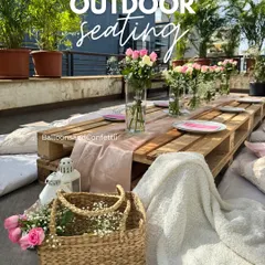 A closer look at the outdoor picnic seating. The low pallet table is adorned with a simple runner, fresh flowers, and comfortable cushions for a relaxed vibe.