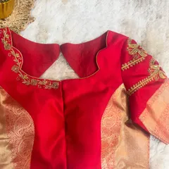The back view of a red blouse, showing a simple yet elegant cut that complements the heavily embroidered sleeves and brocade panels.