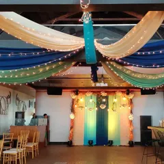 For this Mehendi function, we decorated the ceiling with vibrant drapes in shades of blue, green, and cream, all interwoven with fairy lights. The decor created a festive and colorful atmosphere inside the venue.
