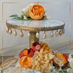 A detailed view of the two-tiered stand from our mother-of-pearl ring platter set. The dangling pearl details and the vibrant orange flower on top create a stunning focal point for the ceremony.