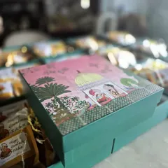 We believe a gift should feel special from the moment you see it. This is a close-up of one of our decorative gift boxes, featuring beautiful traditional artwork. Inside, each snack is carefully packed to ensure it arrives fresh and full of flavour, ready to be enjoyed.