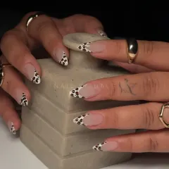 Wild, chic, and oh-so-trendy. This close-up shot highlights the detail of our cow print French tips on almond-shaped nails.