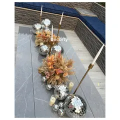 For the 'Disco Night' theme, I created this chic table centerpiece. It combines disco balls of various sizes with dried pampas grass, delicate flowers, and tall candlesticks for a modern bohemian vibe.