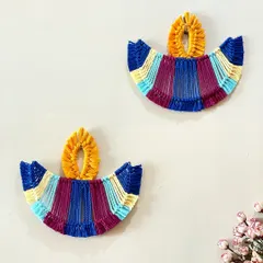A pair of colorful macrame diya hangings. These are a modern, reusable alternative to traditional diyas and add a festive touch to your walls during Diwali.