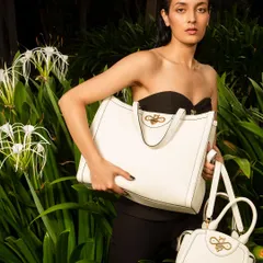 A sleek and sophisticated campaign shot for Koxoxo luxury bags. The wet-look hair and lush green background create a high-fashion, tropical mood that makes the white leather tote pop.