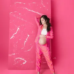 Striking a pose in this vibrant pink suit. The monochrome background makes the color pop, creating a high-fashion and unforgettable maternity portrait.
