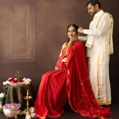 A beautiful moment between an expecting couple. The husband-to-be gently places flowers in his wife's hair, a tender gesture captured in a traditional setting.