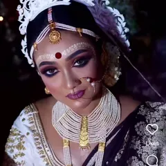A stunning Bengali bride wearing a traditional multi-layered pearl necklace and gold-plated jewellery. The look is completed with the iconic 'mukut' and 'topor'.