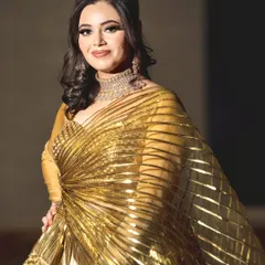 A show-stopping reception look in a metallic gold gown. The makeup is pure glamour, with a soft smokey eye, contoured cheeks, and a sophisticated hairstyle.