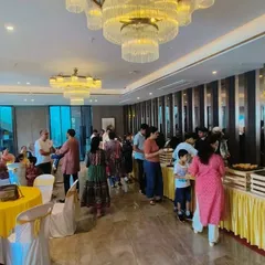This image captures the lively atmosphere of a house warming party we catered. Guests are seen enjoying the buffet spread in a beautifully decorated banquet hall, a service we are proud to provide.