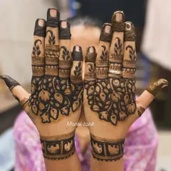 This design features bold, dark-filled floral patterns on the palms, contrasted with delicate leafy designs on the fingers. This style creates a striking and modern look for any bride.