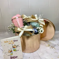 There's no buddy like my sister. This rose gold hamper is curated for a sister, featuring a personalized tumbler and other pampering gifts, all tied together with beautiful bows and flowers.