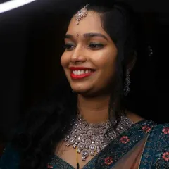 A happy bride at her reception. Her look features a bright red lip, softly curled hair, and sparkling diamond-style jewellery, creating a fresh and modern bridal style.