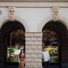 A stylish, symmetrical portrait using the beautiful architecture of a city building. This is modern urban romance.