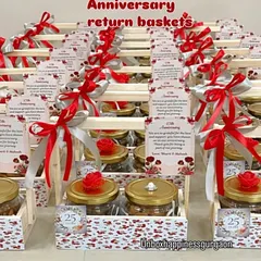 A large batch of 25th-anniversary return baskets, decorated with red and silver ribbons and personalized thank you cards.
