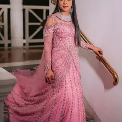 A full length view of the hand beaded pink gown. The elegant drape, sheer sleeves, and sparkling embellishments create a look that is both sophisticated and incredibly glamorous.
