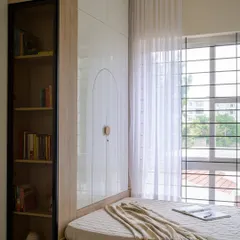 This view shows the full-height wardrobe and a tall, glass-fronted bookshelf, providing extensive storage for a growing child's needs in a bright and organized way.