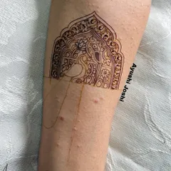 An outline of a peacock within an ornate arch for a baby shower mehendi. This shows the initial sketch for a design that combines both divine and decorative elements.